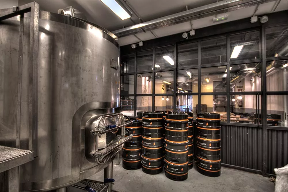 Vista de la sala de cocción con barriles apilados en el brewpub de Sant Andreu de Garage Beer Co., en Barcelona.