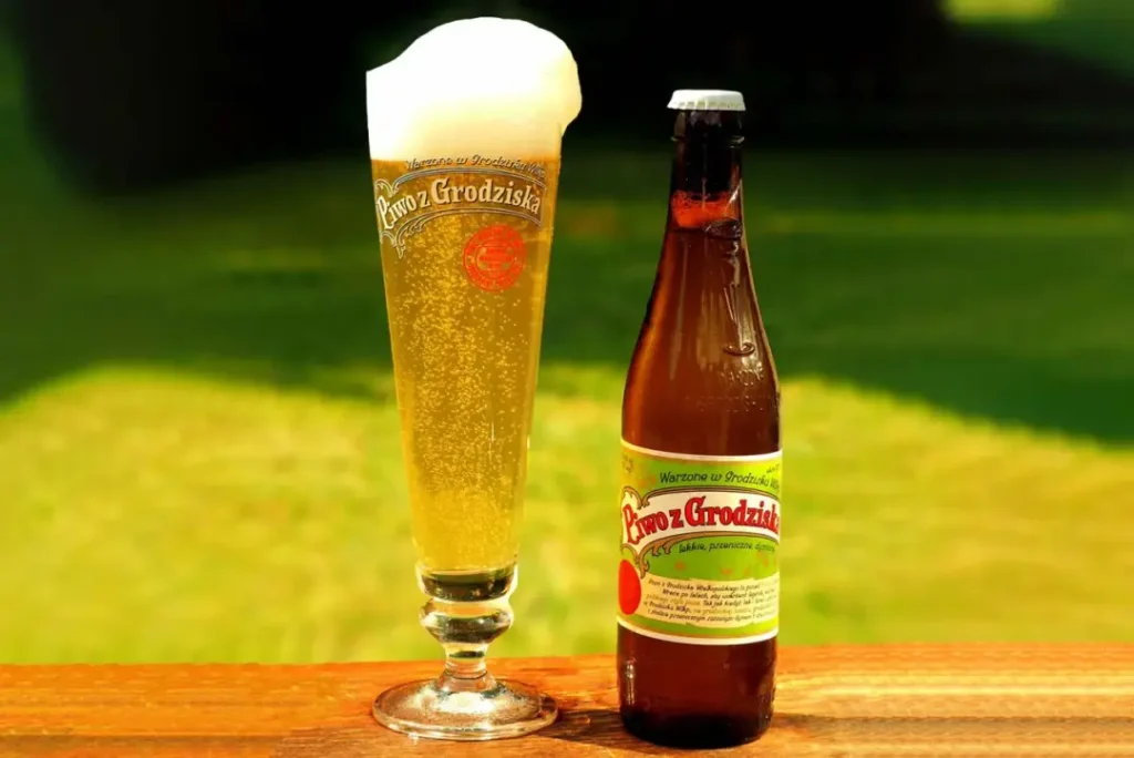 Piwo Grodziskie servida mostrando su color dorado pálido y espuma blanca masiva